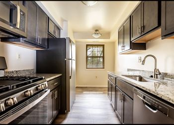 A kitchen with dark cabinets and white countertops